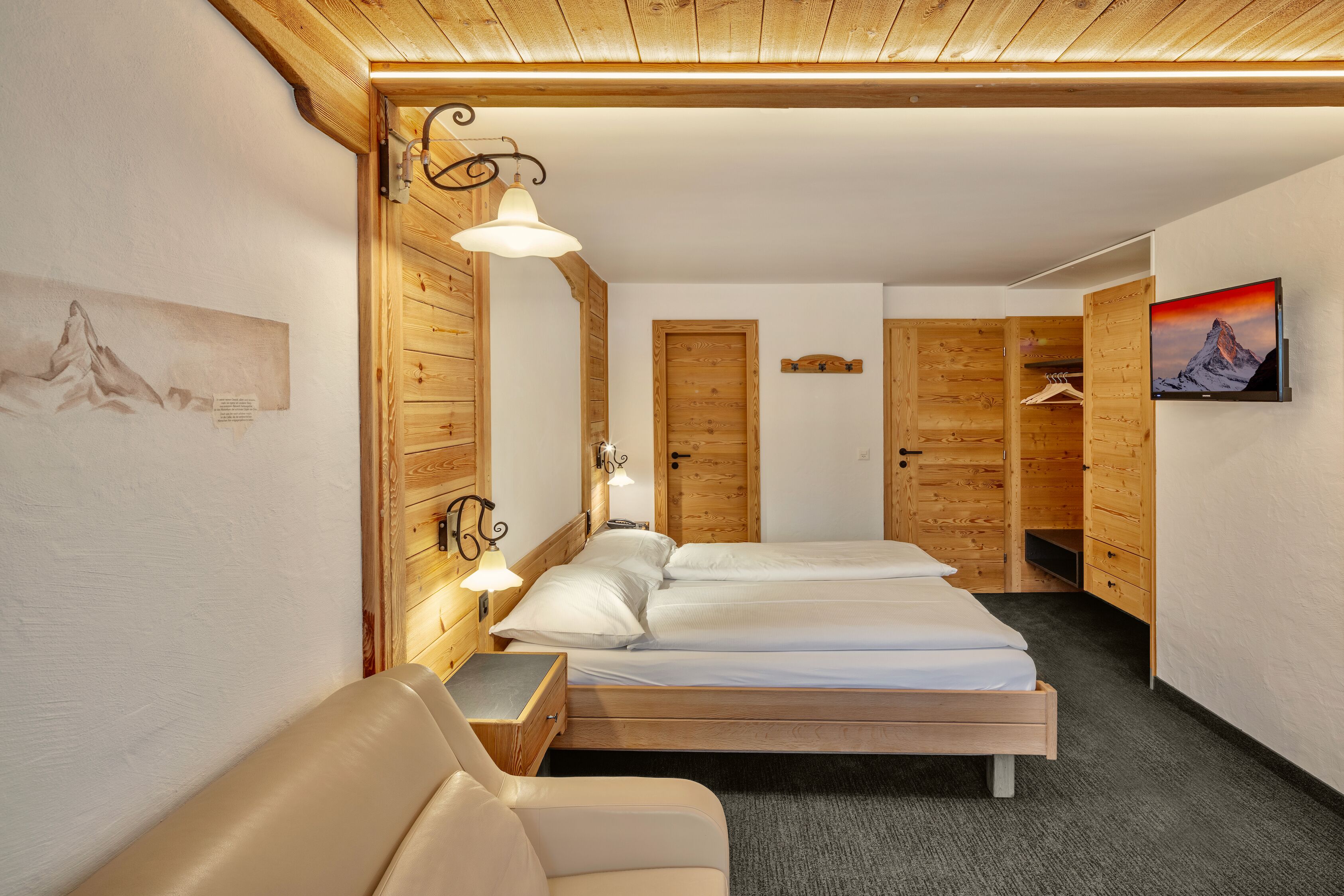 A cozy room with a bed, a chair, a wooden wardrobe, and a TV.