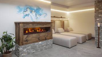 A modern living room with a stone fireplace, a sofa, and a potted plant.