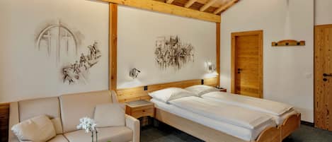 A bedroom with a wooden ceiling, a bed, a nightstand, a lamp, a sofa, and a wall with artwork.