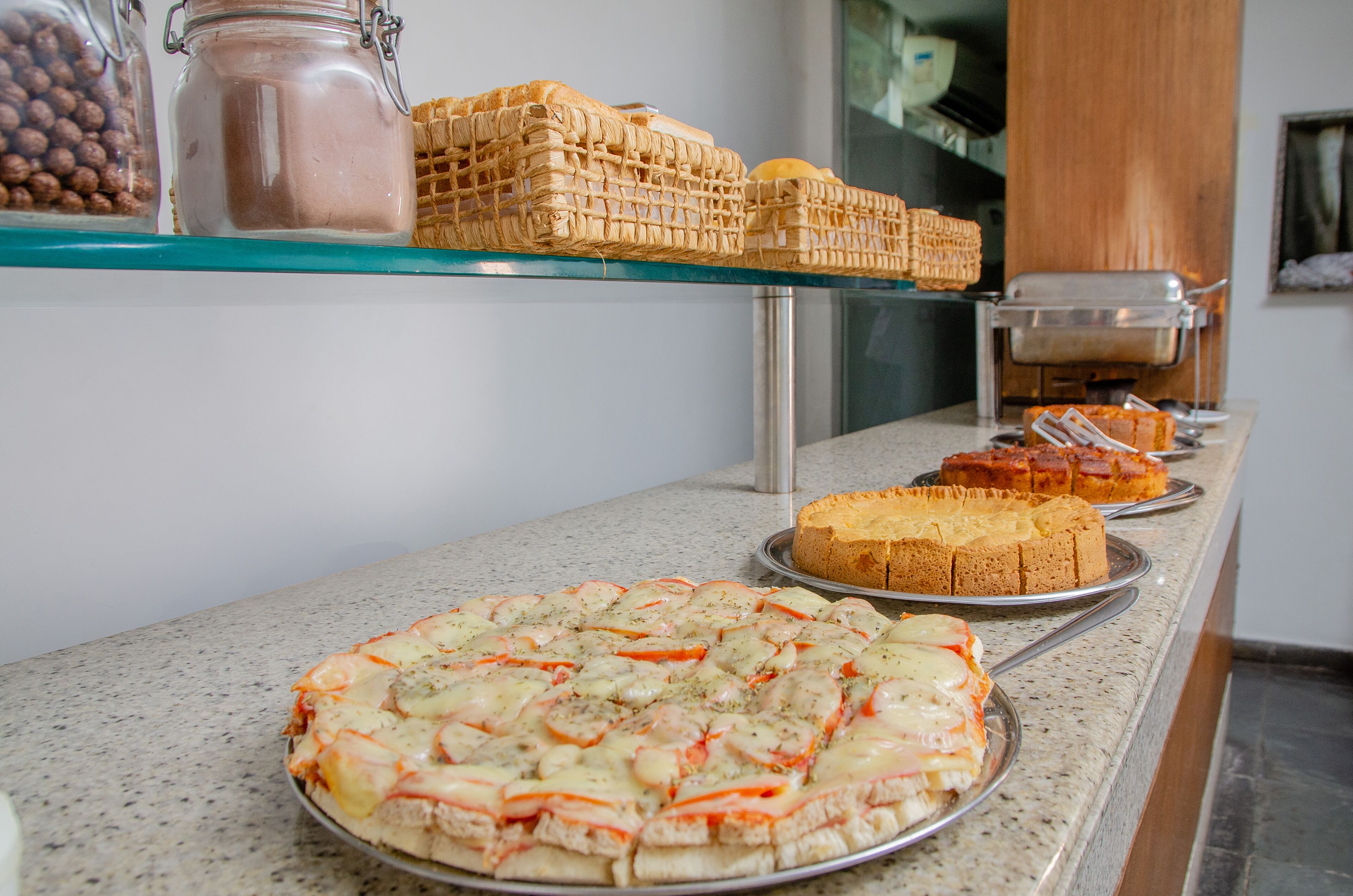 A buffet with various food items including a pizza, bread, and a cake.