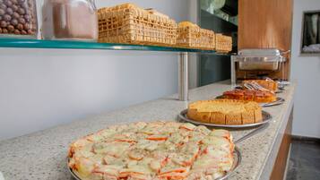 A buffet with various food items including a pizza, bread, and a cake.