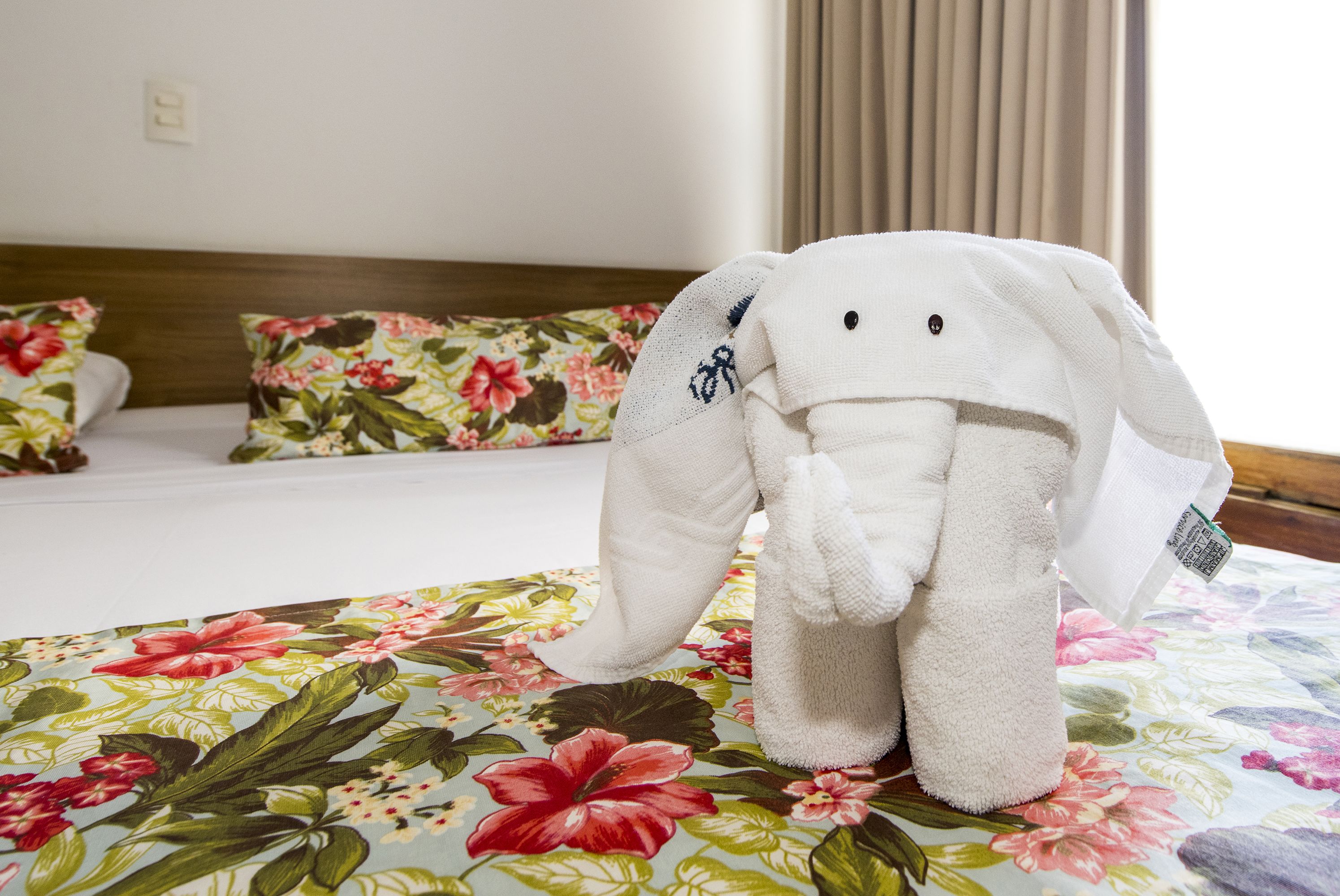 Ein weiches, elefantenförmiges Kissen auf einer floralen Hotelbettdecke.