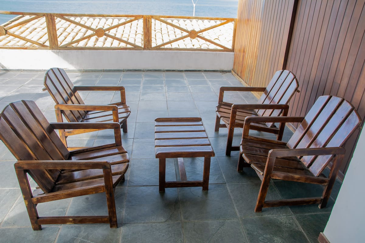 Une terrasse avec des chaises et une table en bois, donnant sur une plage.