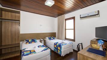 Habitación de hotel con dos camas, techo de madera, unidad de aire acondicionado, televisor y escritorio con cesta y menú.