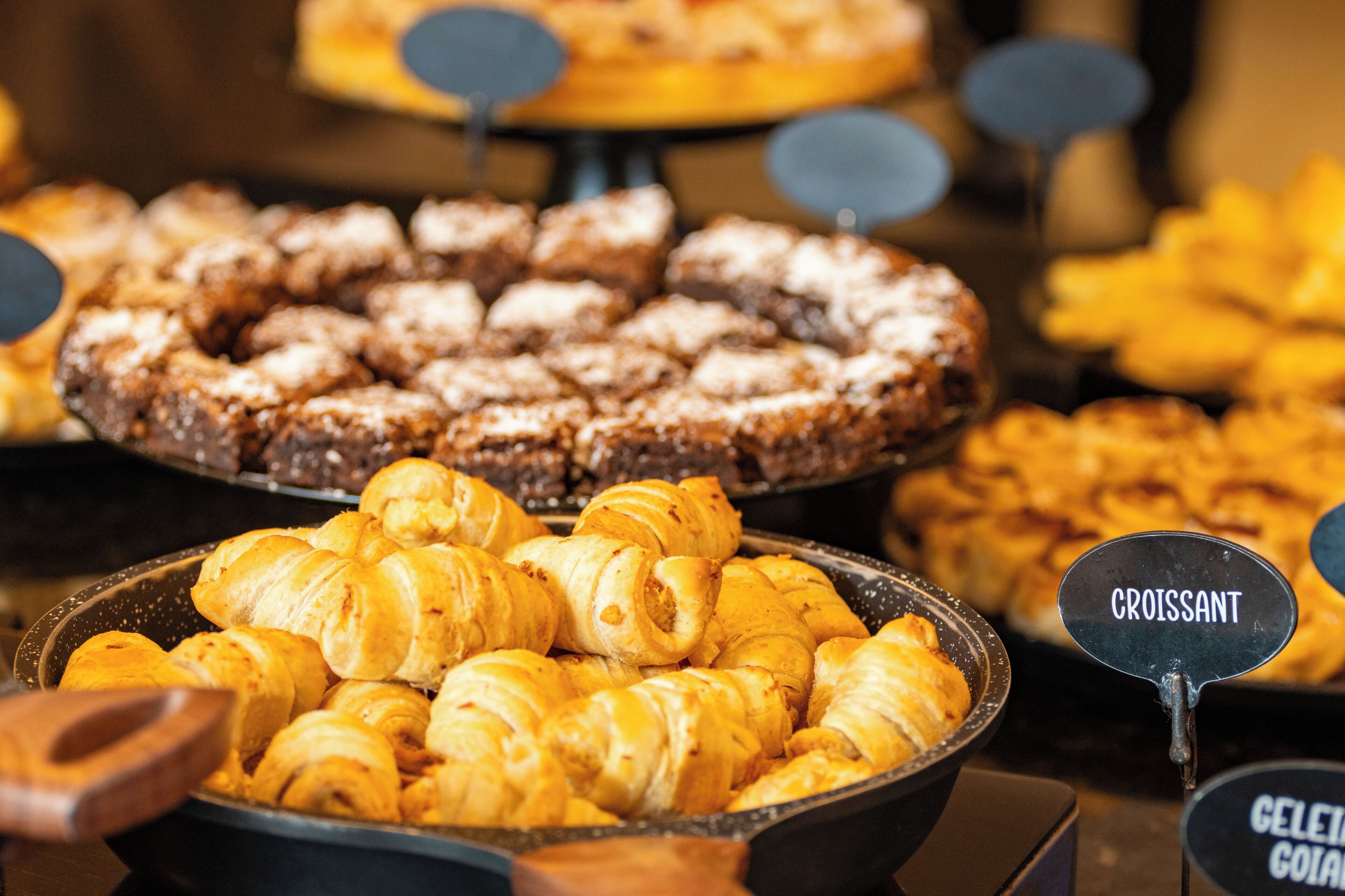 Diversos produtos de panificação, incluindo croissants e outras iguarias, expostos em uma padaria.