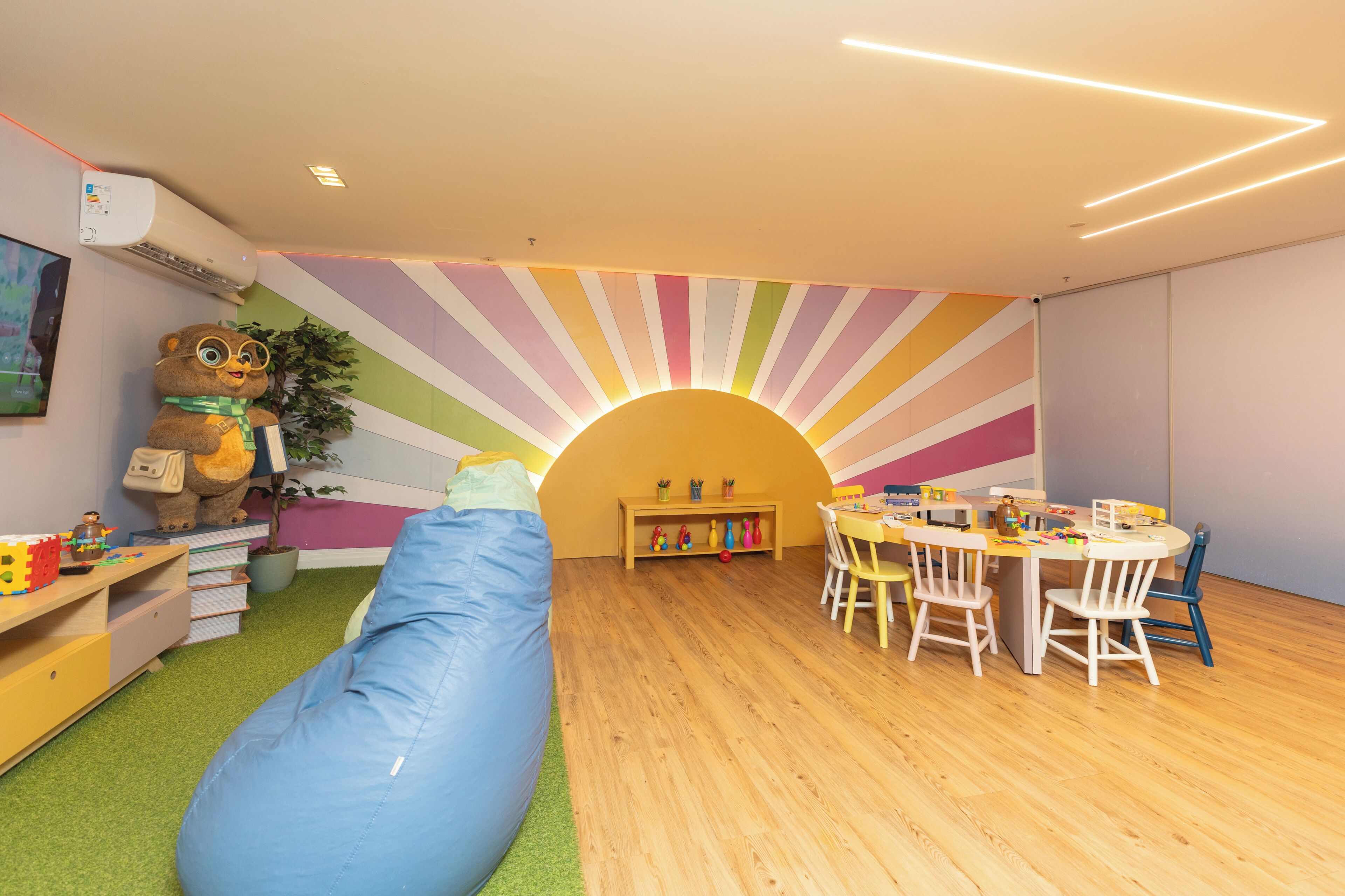 A room with a bean bag, a table with chairs, a bookshelf, and a large stuffed animal.