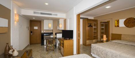 A hotel room with two beds, a desk with a TV, a dining area, and a closet.