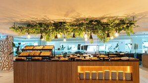 Un área de bufé con diversas opciones de comida, una barra de madera y plantas colgantes.