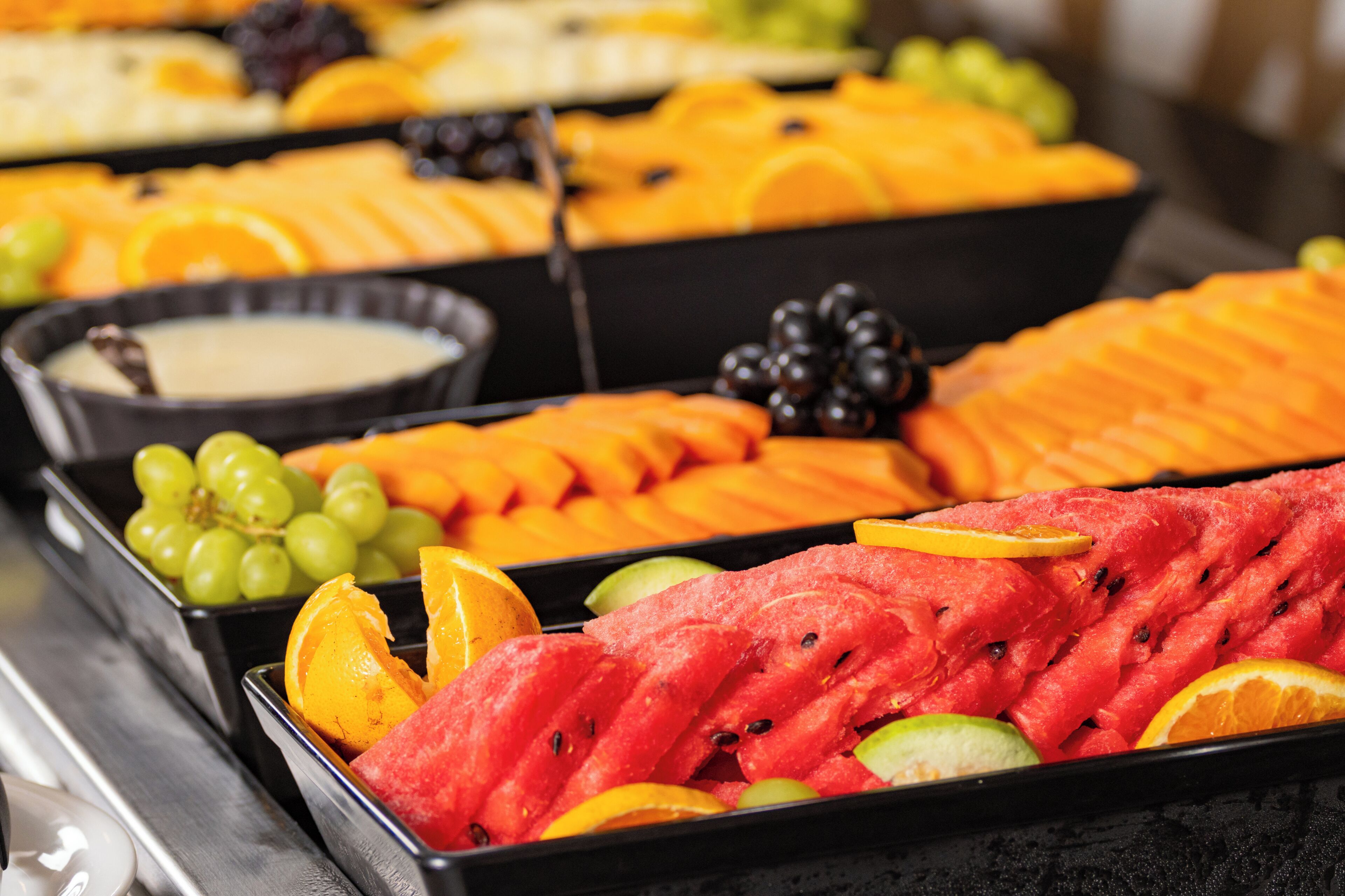 A fruit display with various types of fruits and a bowl of dip.