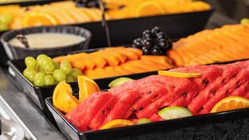 A fruit display with various types of fruits and a bowl of dip.