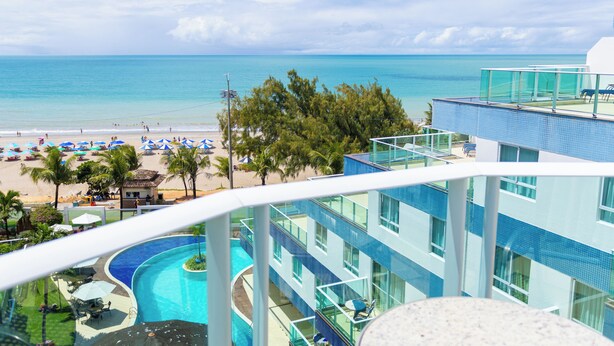 Un hotel con piscina, vista a la playa y balcón con vista al océano.