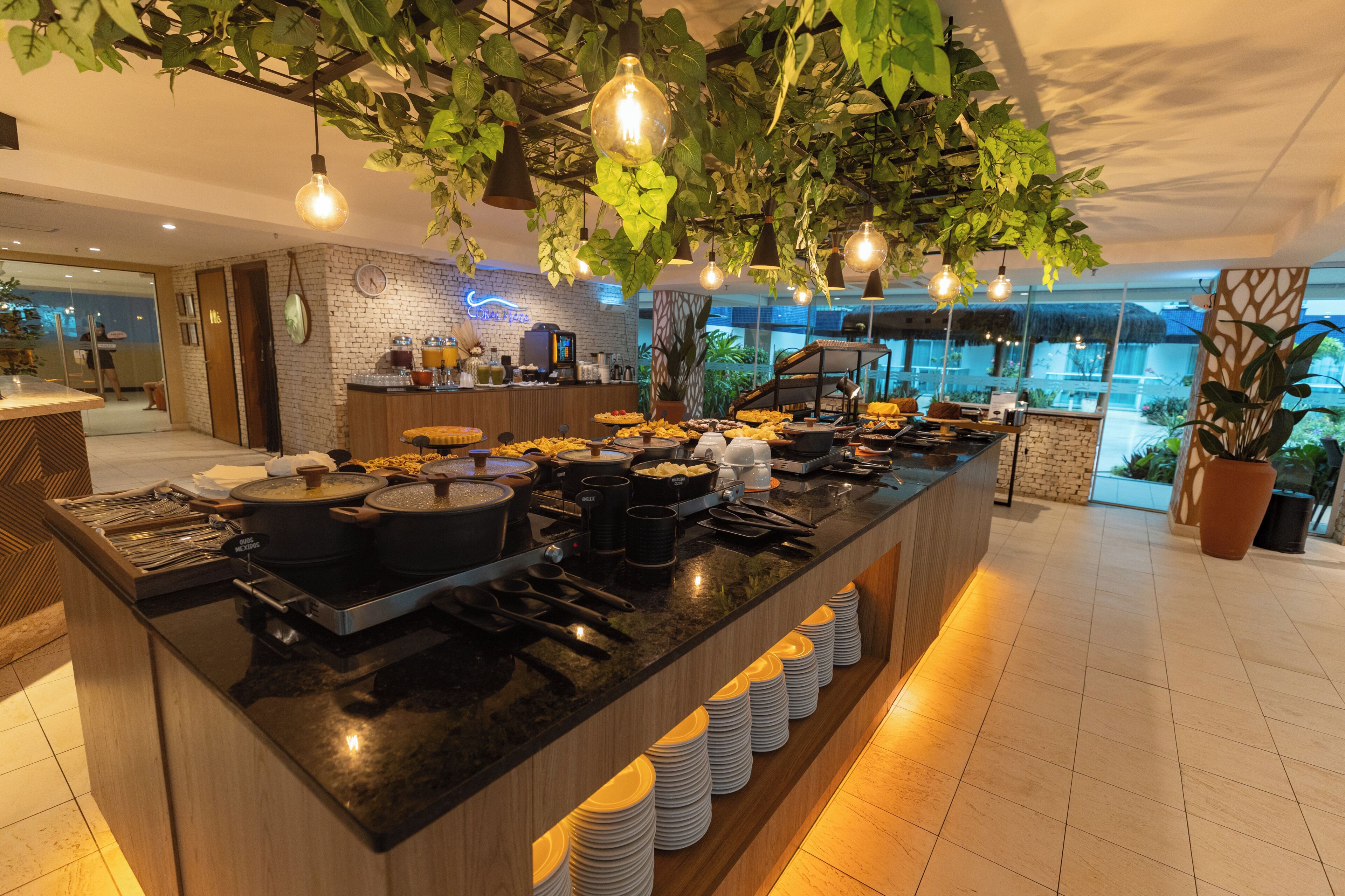 Un buffet garni de divers plats et d’ustensiles de cuisine, une horloge au mur et une vue sur l’extérieur.