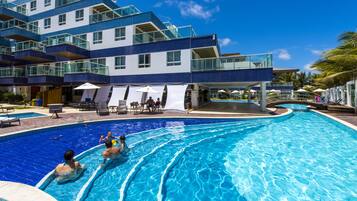 Una piscina al aire libre, sombrillas, sillones reclinables de piscina