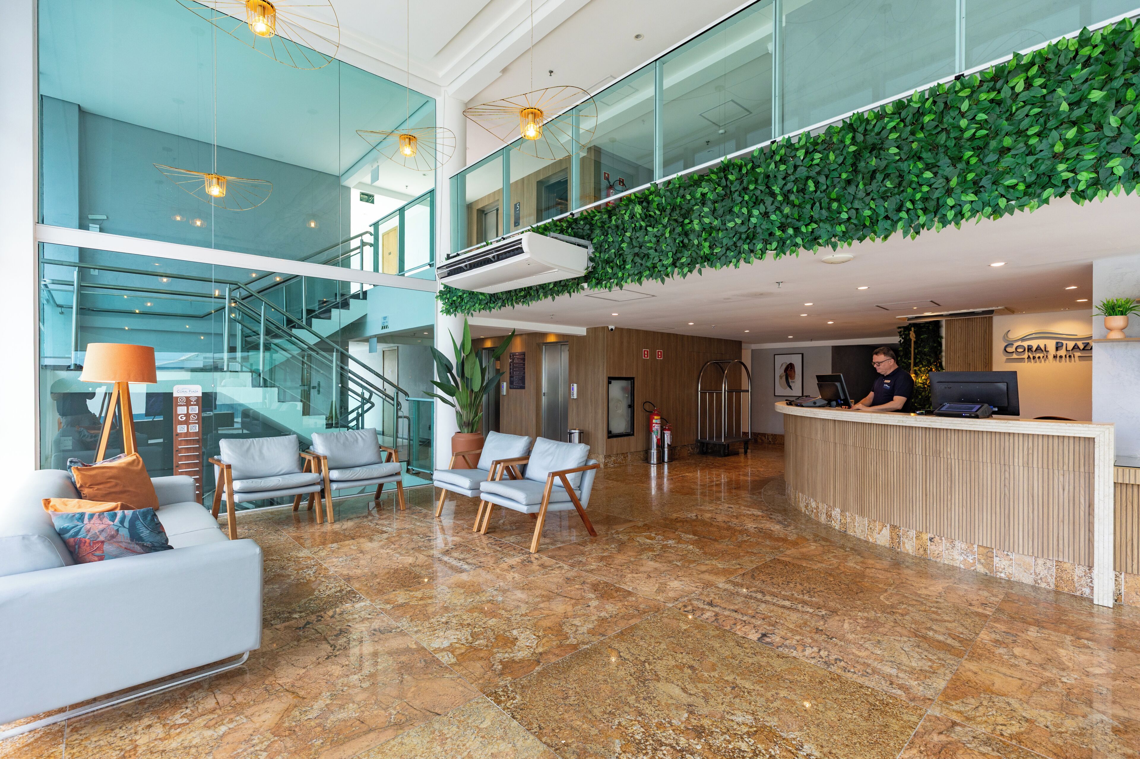 Eine Hotelhalle mit Empfangstresen, Sitzgelegenheiten, einer Treppe und einer grünen Wand.