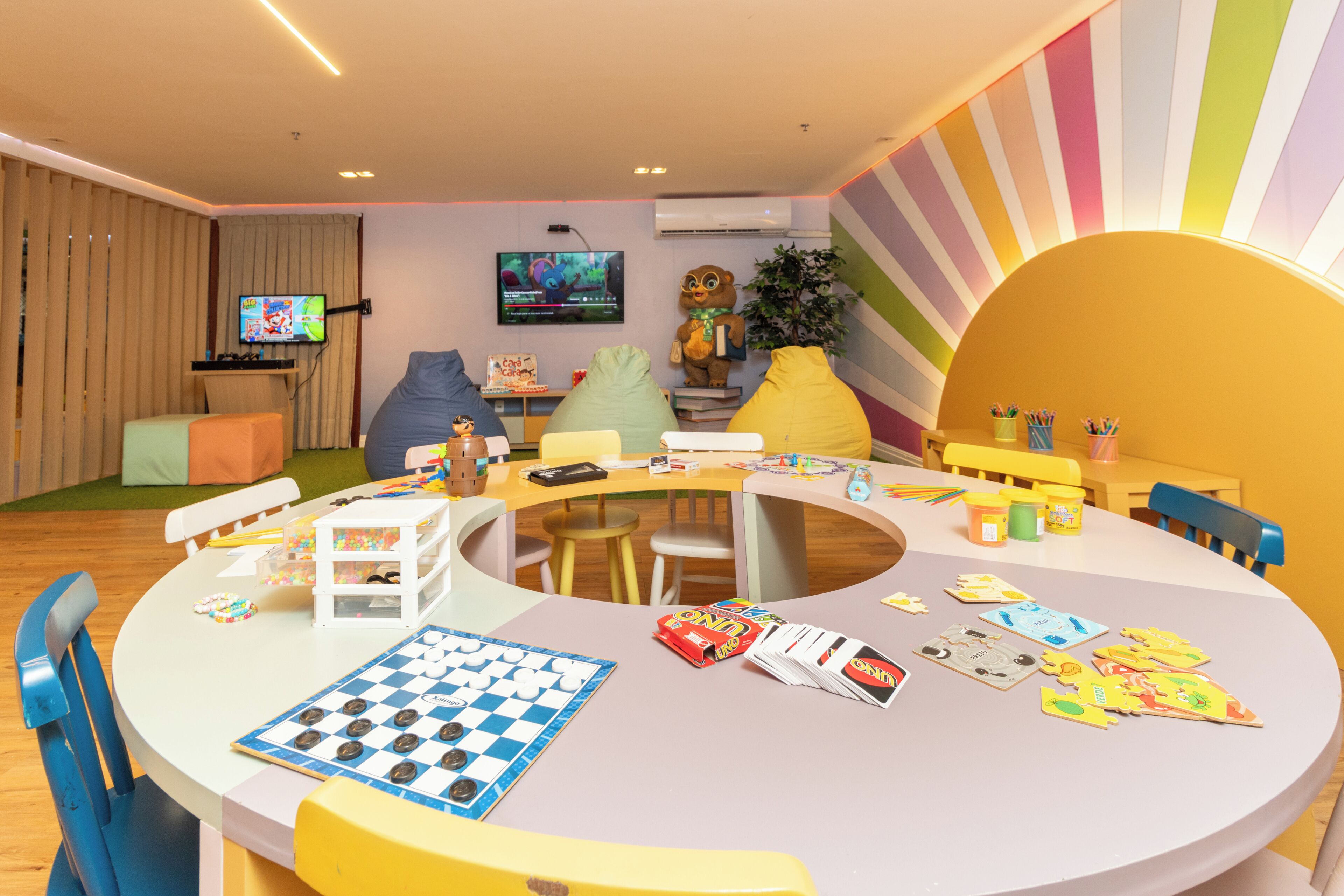 A children's play area with a checkered game board, toys, and a television.