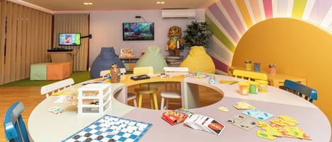 A children's play area with a checkered game board, toys, and a television.