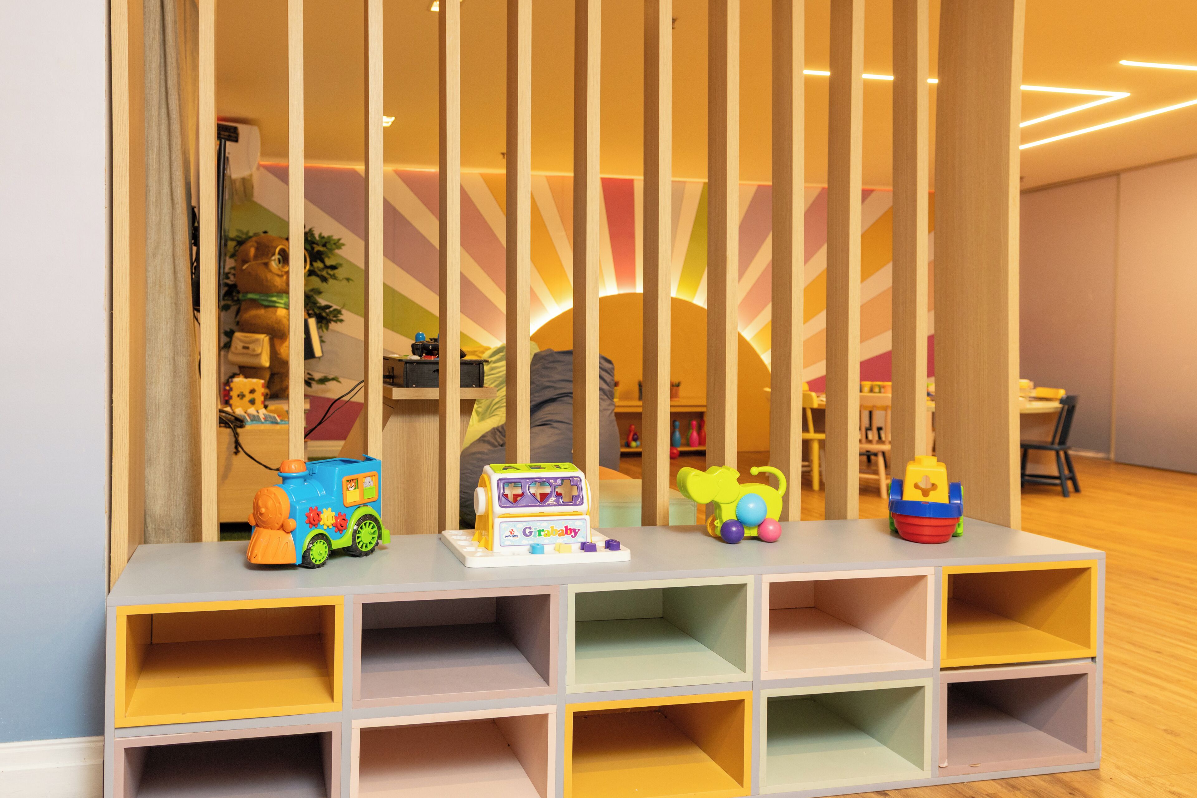 A children's play area with a table, toys, and a colorful wall design.