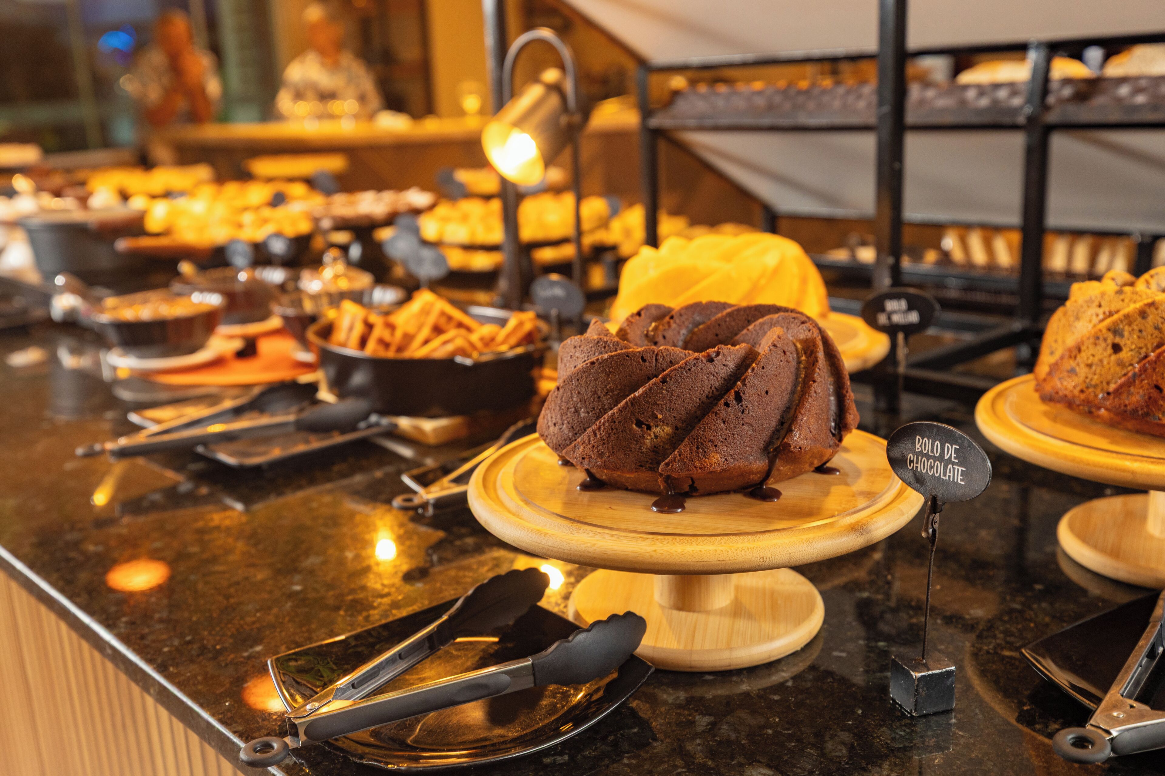 Un mostrador de buffet amb diverses fornaderies, incloent una cassola de xocolata, i un senyal que indica un postre de xocolata.