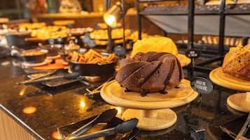 Un mostrador de buffet amb diverses fornaderies, incloent una cassola de xocolata, i un senyal que indica un postre de xocolata.