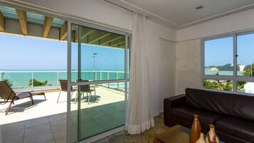 Sala de estar moderna com porta de vidro que dá para uma varanda com vista para o mar.