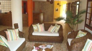 Una habitación acogedora con muebles de mimbre, suelo de piedra y una mesa de centro de madera.