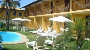 Un hotel con zona de piscina, tumbonas y sombrillas.