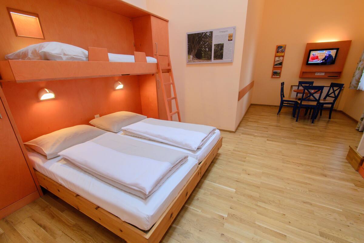 Una habitación con literas, un escritorio y un televisor.