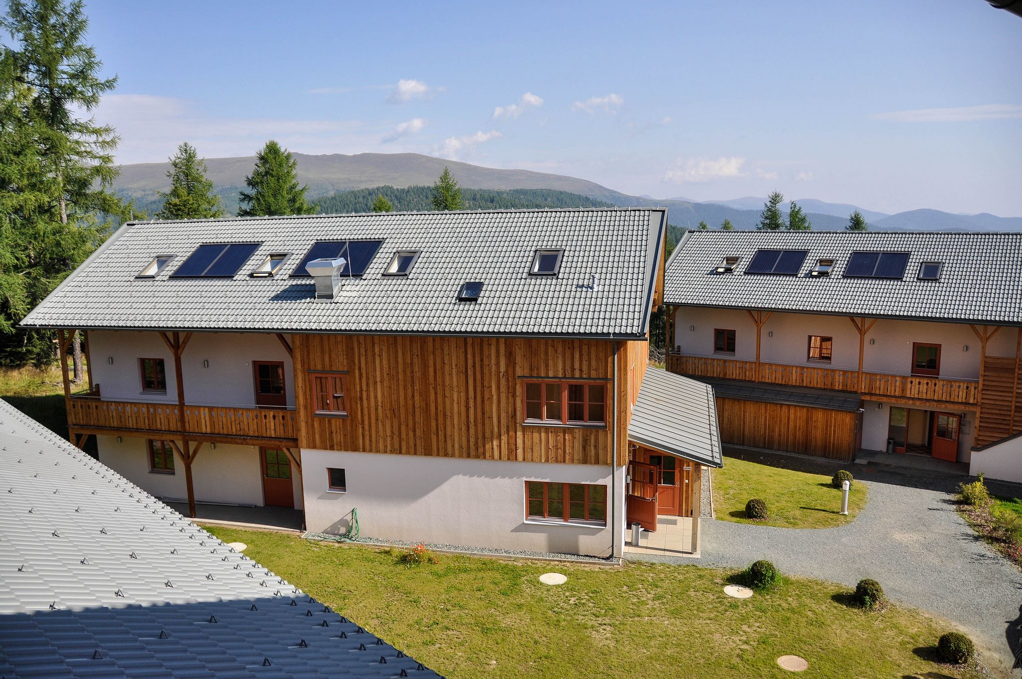 A two-story wooden building with a sloped roof, multiple windows, and a small garden area.