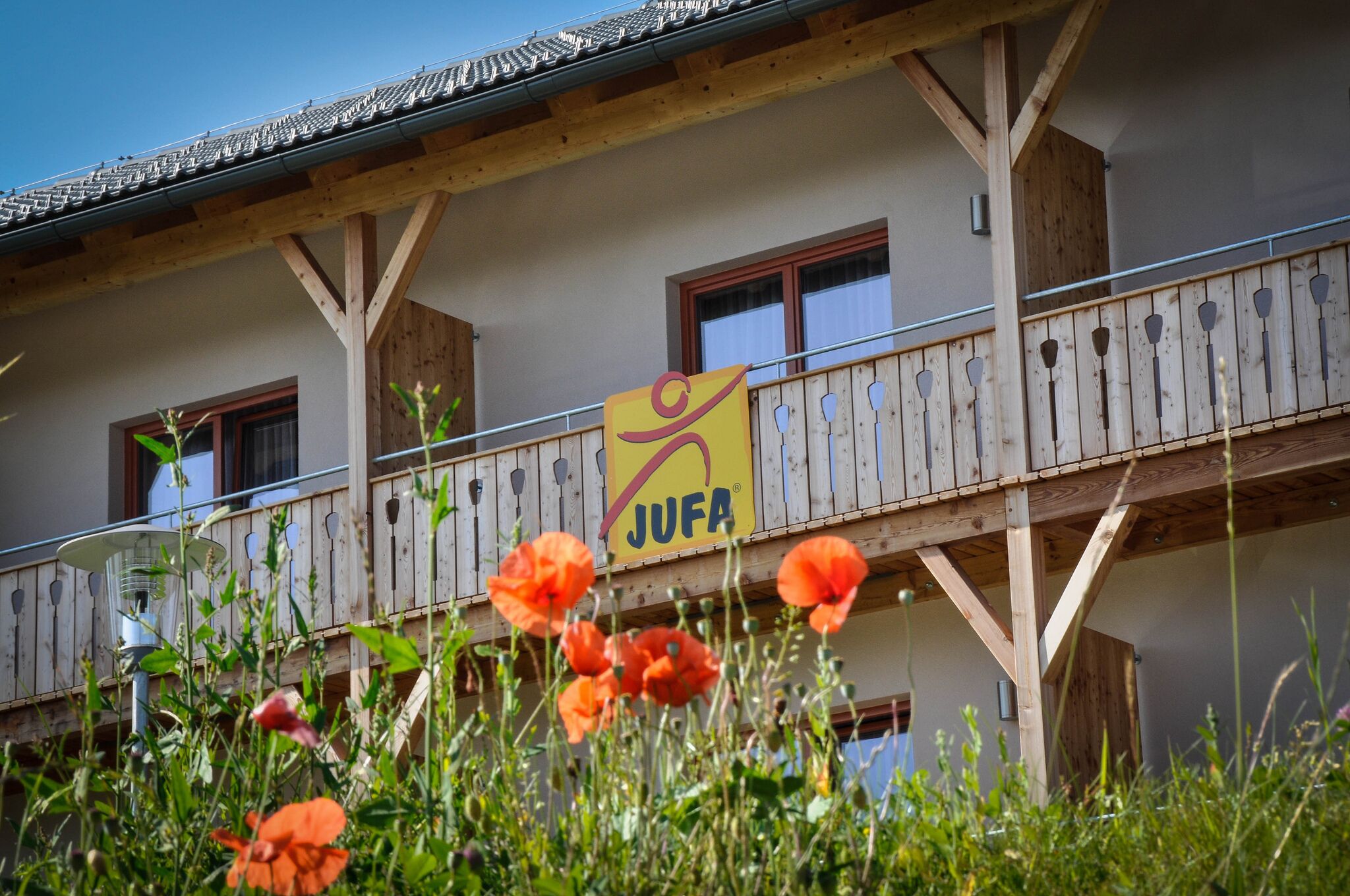 A building with a wooden balcony and a sign reading "JUFA".