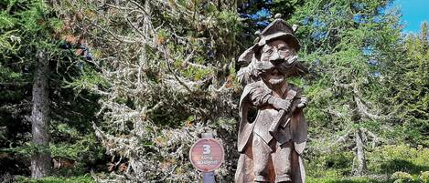 Une statue en bois représentant un homme tenant un fusil, placée à côté d’un panneau sur lequel on peut lire « König Waldgeist ».