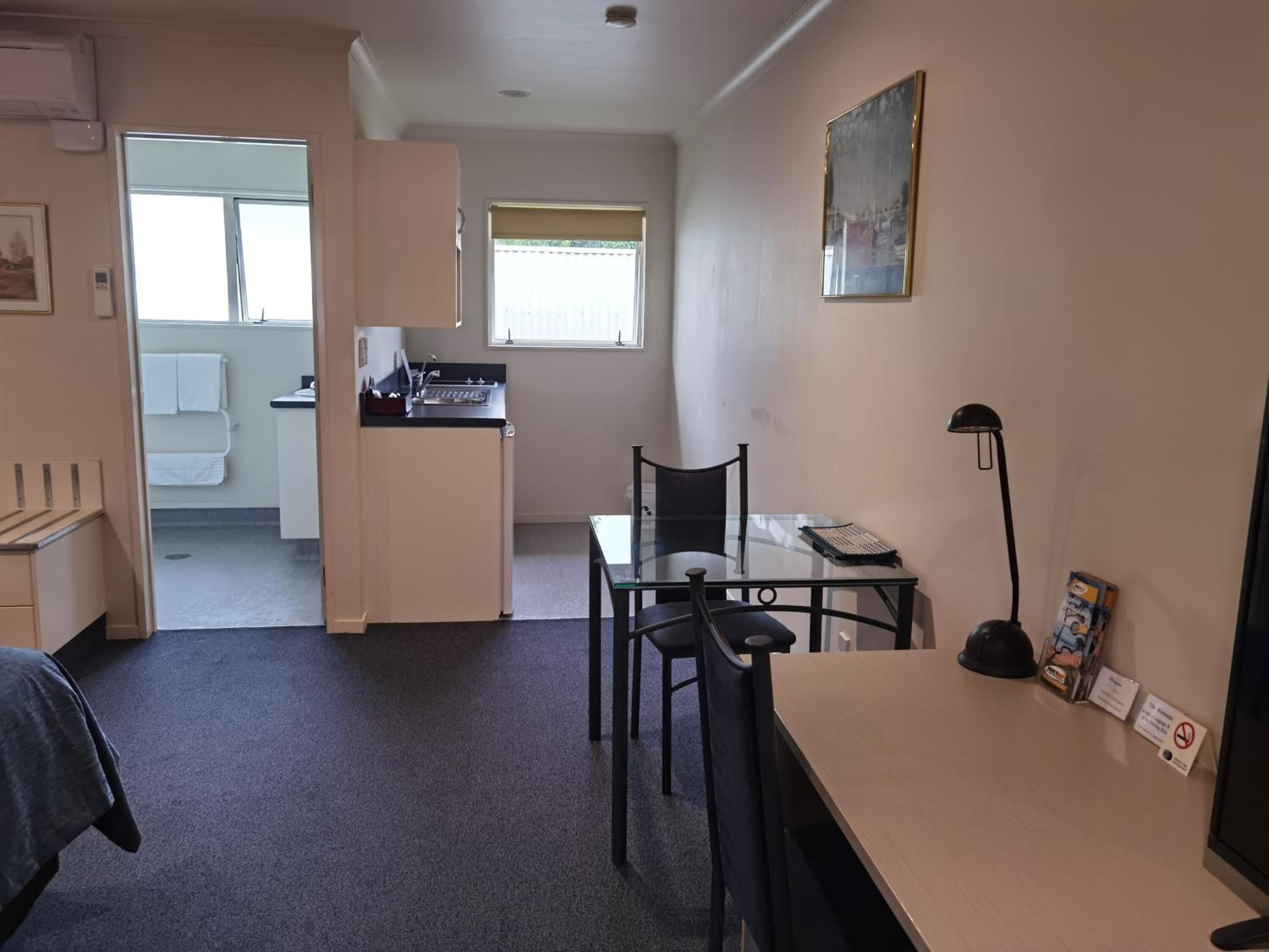 Une chambre d’hôtel compacte comprenant un coin cuisine, un espace repas et une petite salle de bain.
