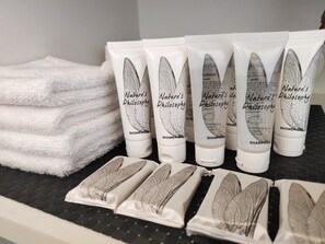 A display of Nature's Philosophy shower gel and shampoo bottles, along with neatly folded white towels. - Harringtons Motor Lodge (Palmerston North)