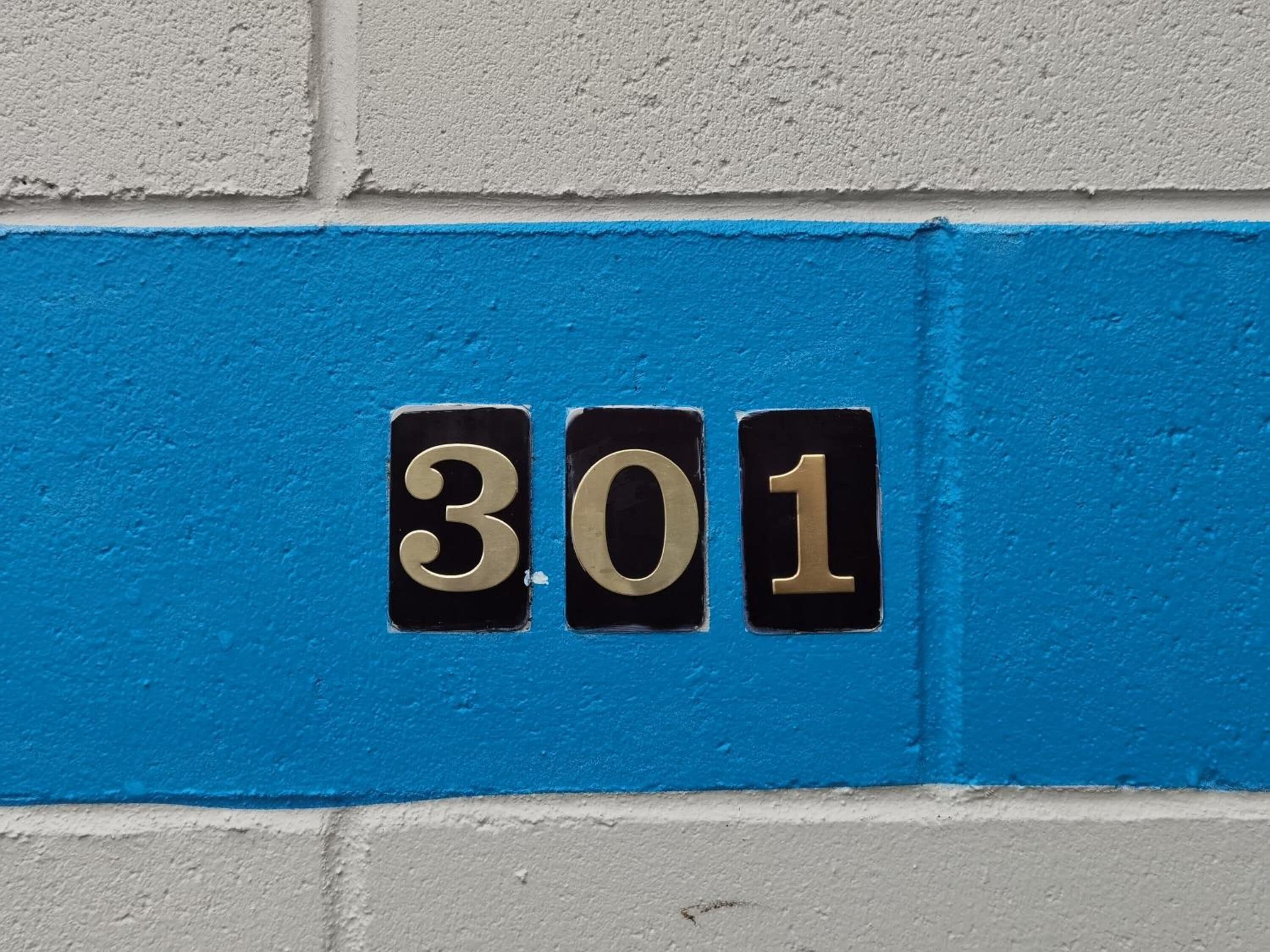 A house number '301' on a blue and white wall.