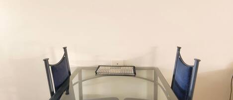 A conference room with a glass table, two chairs, and a framed painting on the wall.