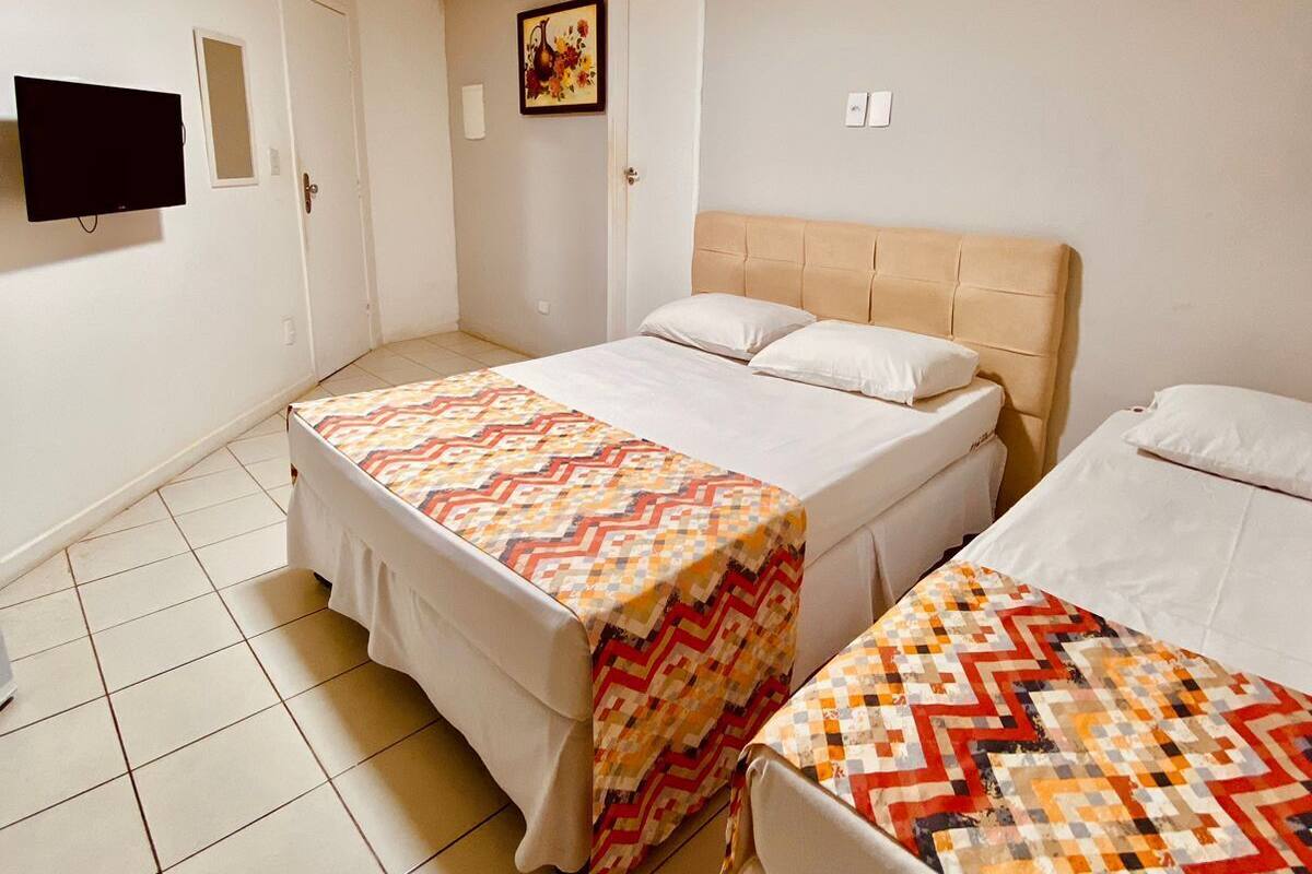 A hotel room with two beds, a TV, and a painting on the wall.