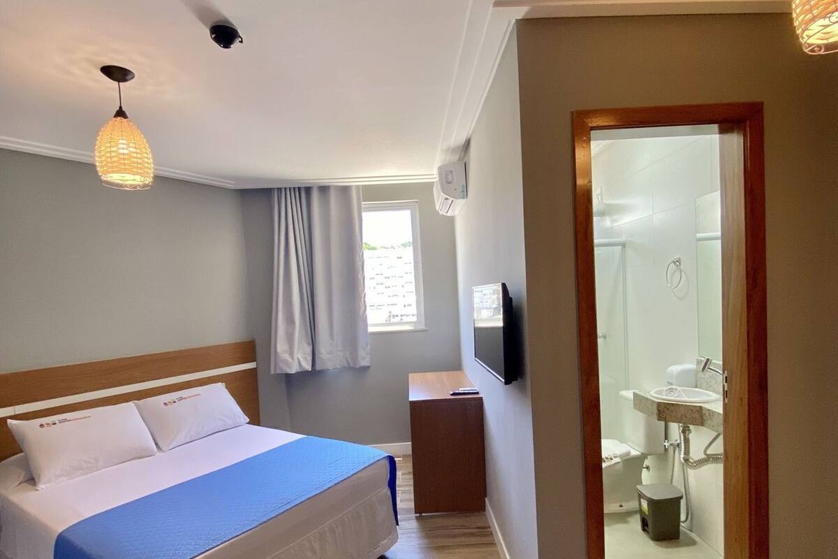 A bedroom with a bed, bedside table, and a TV.