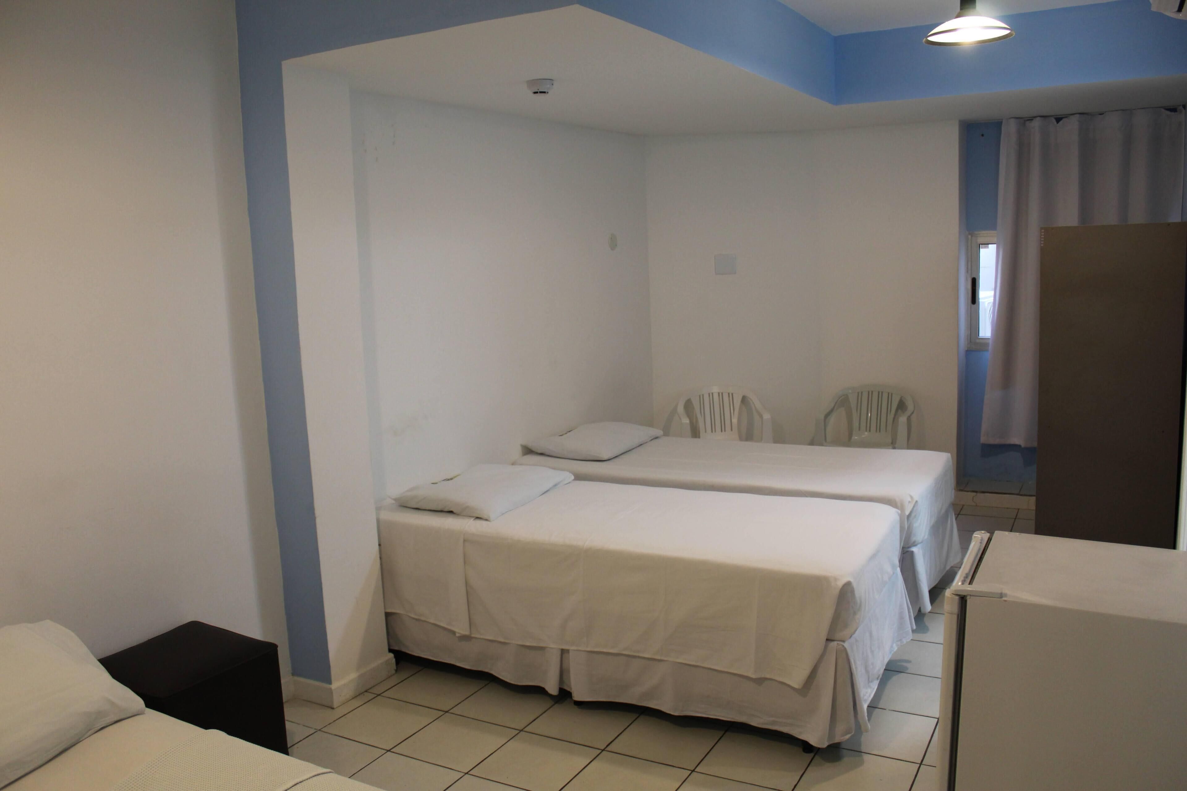 A room with two beds, a small table, and a chair.