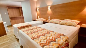 A hotel room with two beds, wooden flooring, and built-in wardrobes.