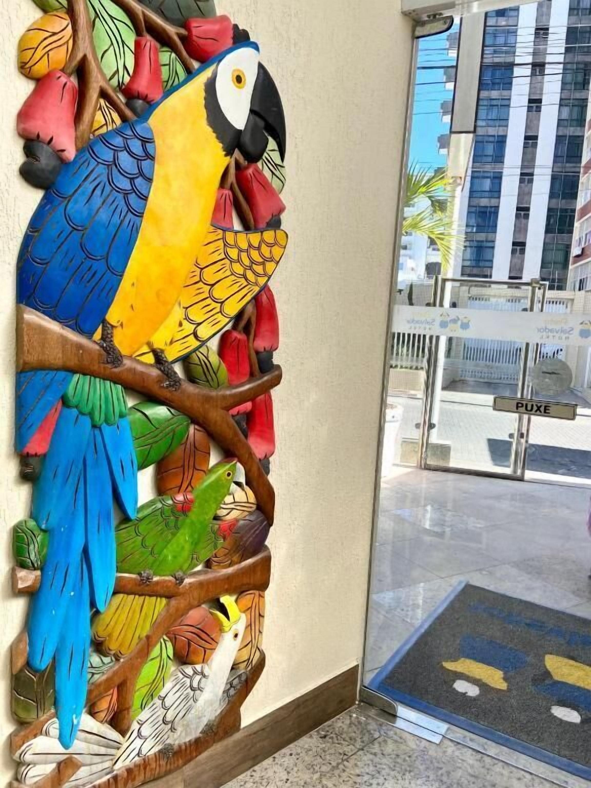 A colorful wooden sculpture of a parrot perched on a branch.