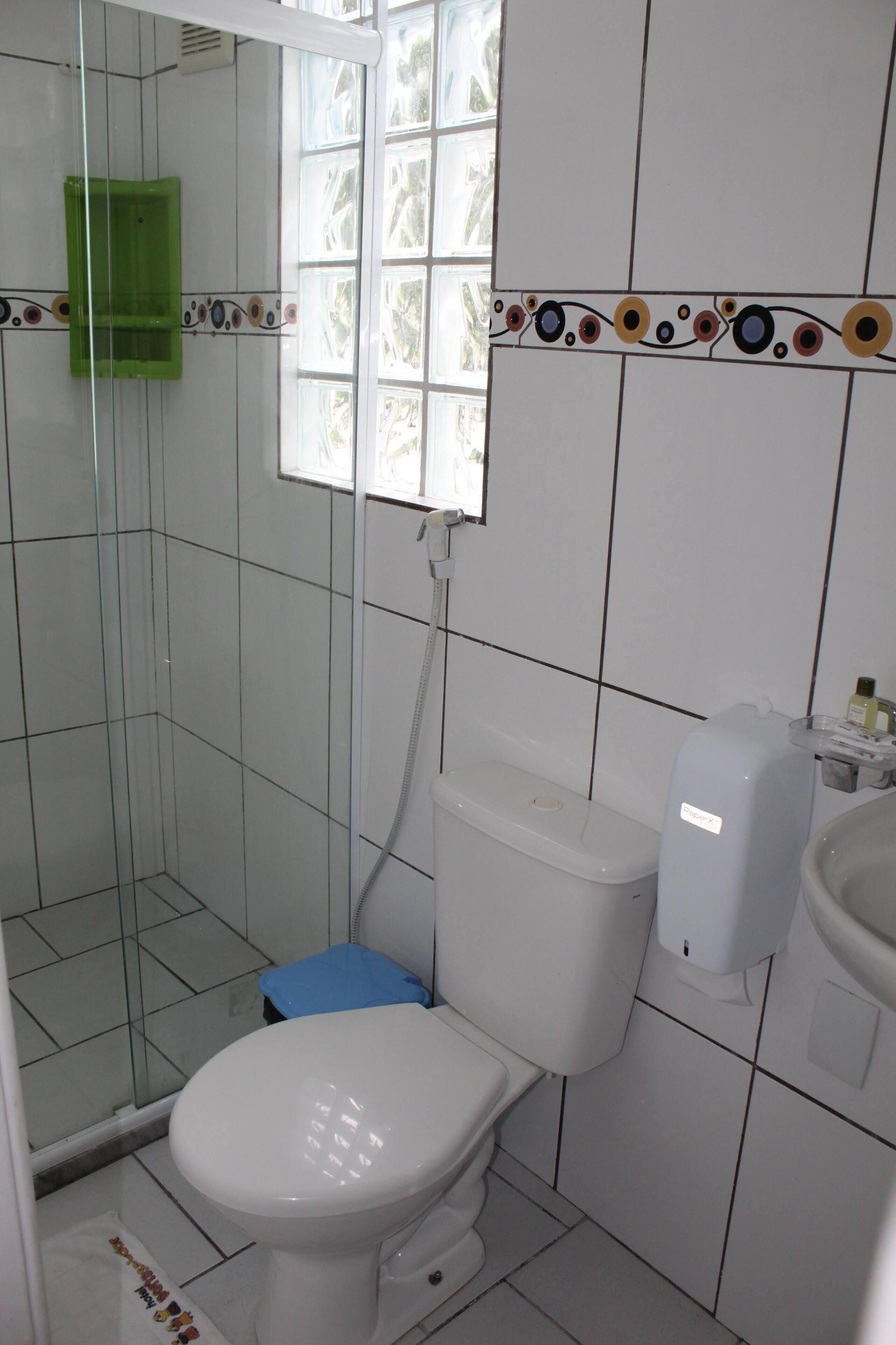 A bathroom with a glass shower enclosure, a toilet, and a window.