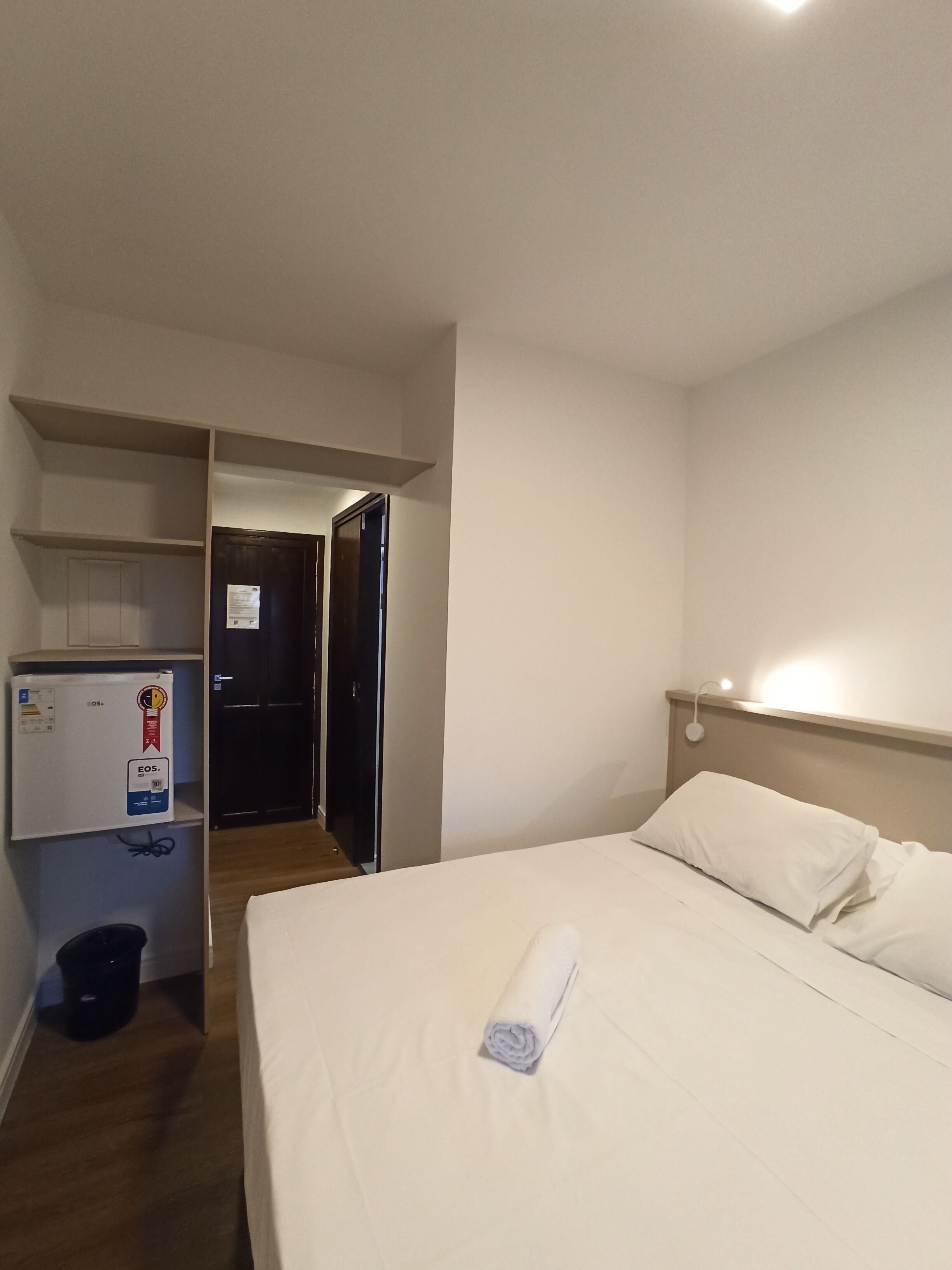A hotel room with a bed, a desk with a computer, and a door leading to another room.