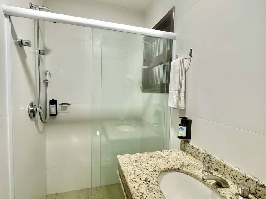 A modern bathroom with a glass-enclosed shower, a granite countertop sink, and a white toilet.