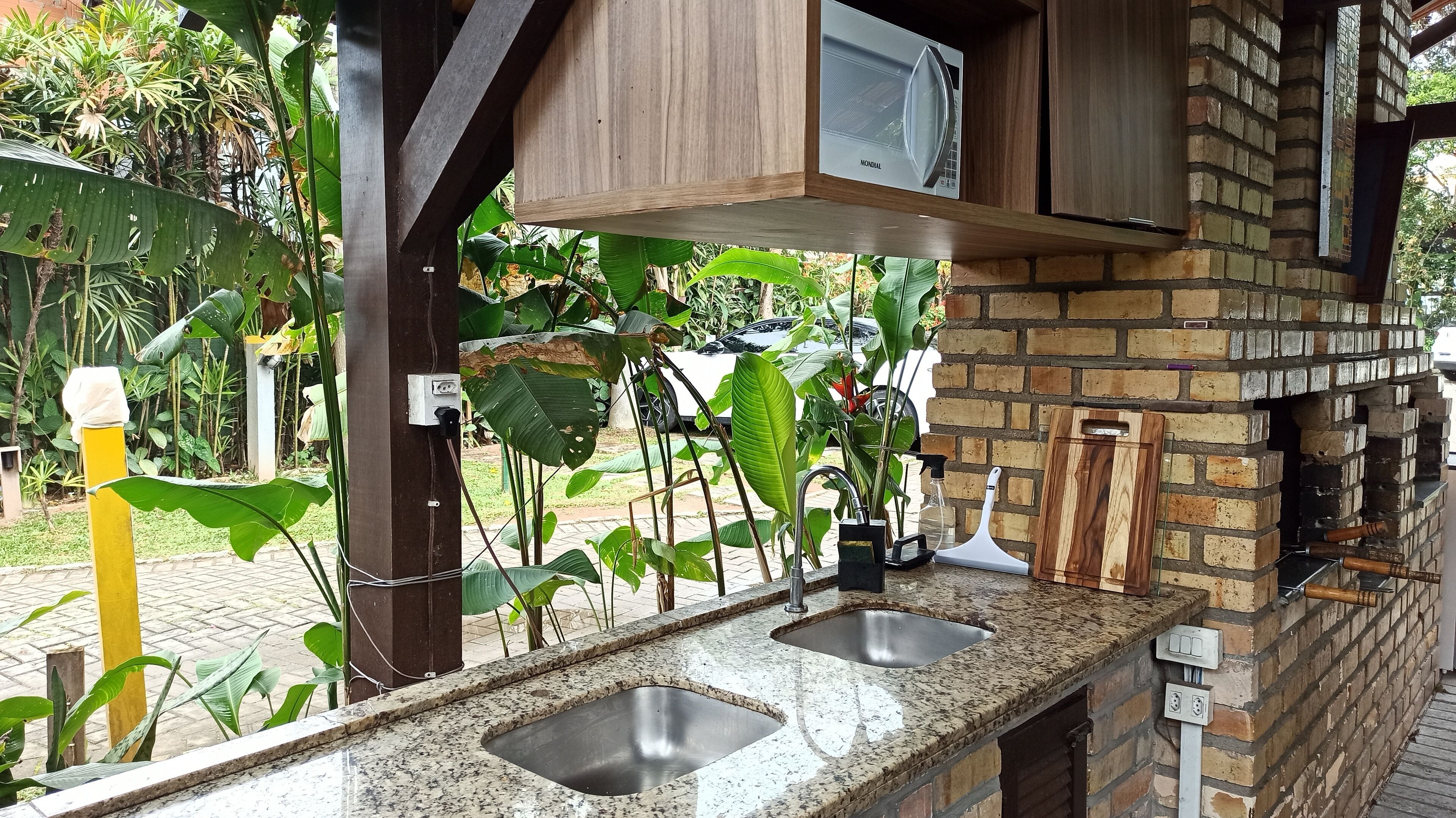 A kitchen area with two sinks, a microwave, and a brick oven.