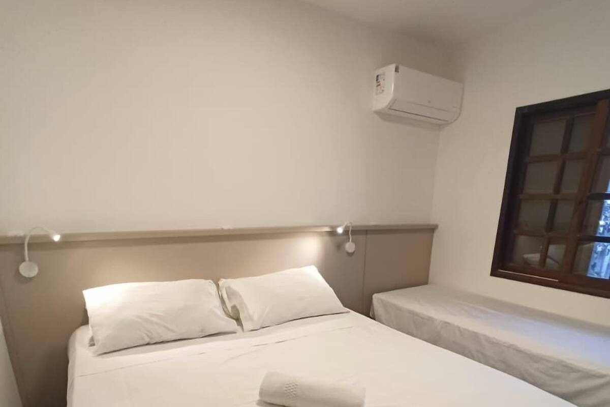 Een hotelkamer met een groot bed, een kleiner bed, een raam en een airconditioning.
