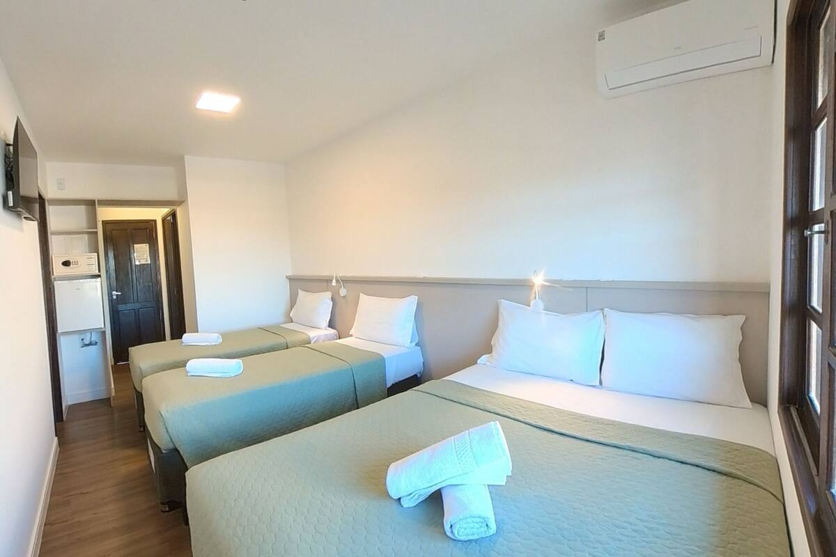 Een hotelkamer met twee bedden, een kleine kitchenette, een deur naar een badkamer en een raam.