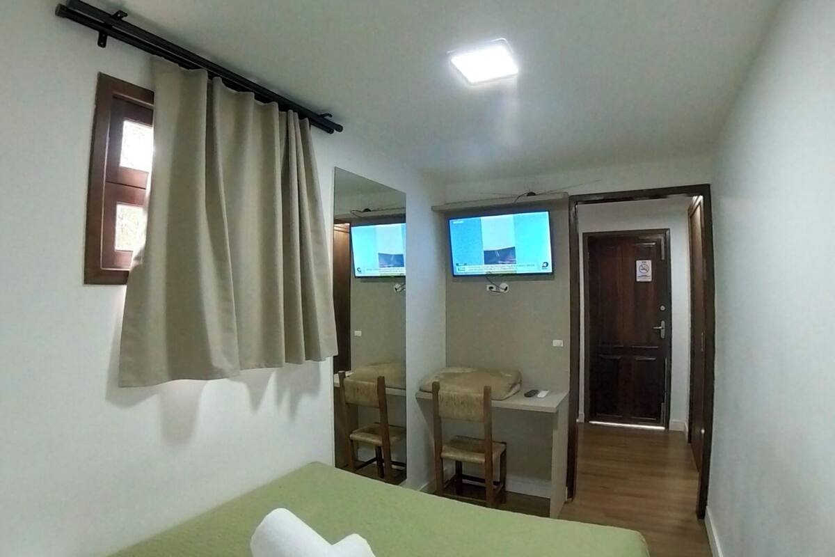 Een hotelkamer met een bed, een bureau, een stoel en een televisie.