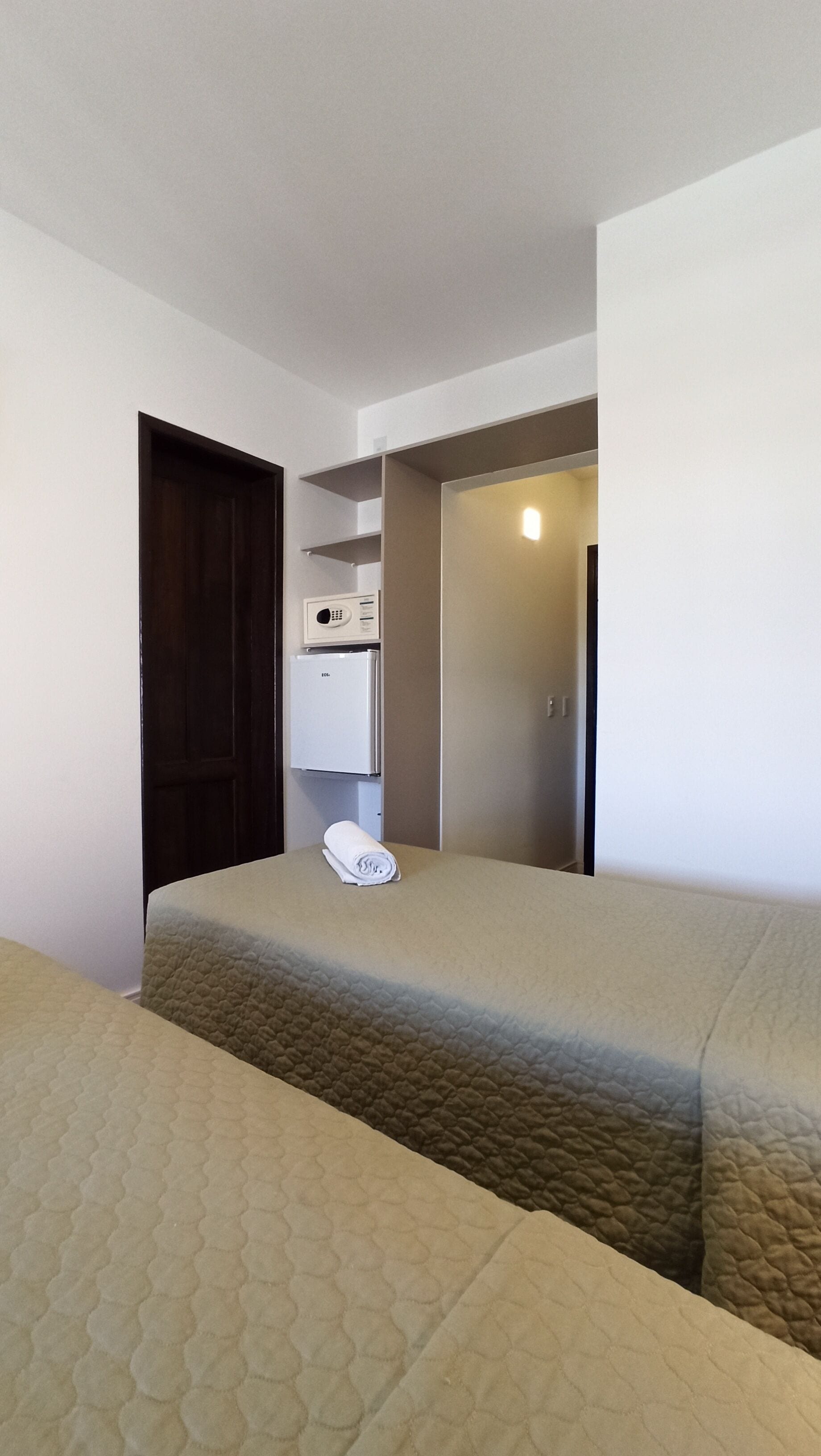 Una camera da letto piccola e ordinata con un letto, un armadio e un forno a microonde.