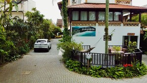 A white car parked on a paved path leading to a building with a sign reading "RECEPTION". - Hotel Natur Campeche (Florianópolis)