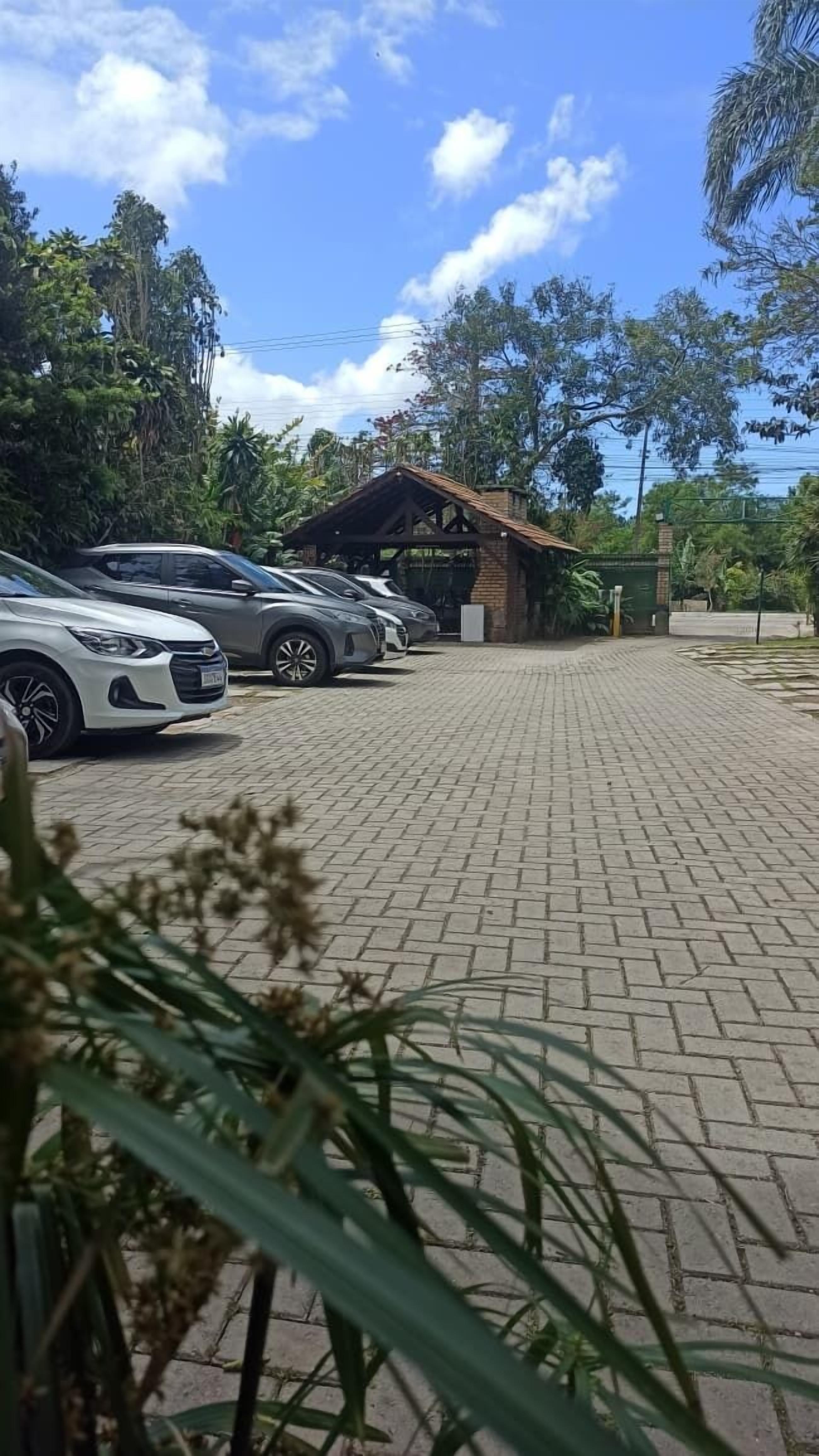 A paved parking area with several cars parked in front of a building with a tiled roof.