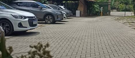 A paved parking area with several cars parked in front of a building with a tiled roof.
